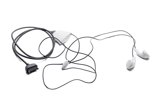 Wired headphones with tangled cords lying on a plain background