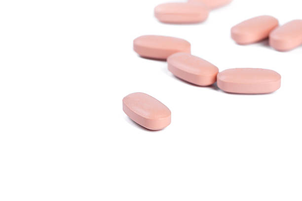 istock Various pink tablets scattered on a white surface with one tablet in focus 2245499109