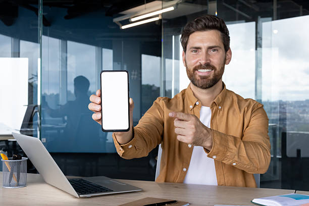 istock Smiling businessman showing smartphone with white screen in office 2245499646
