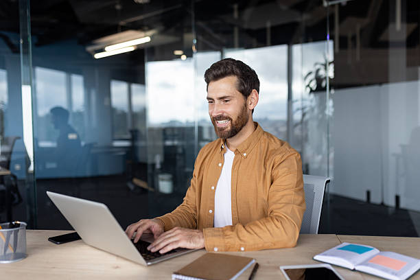 istock Smiling professional using laptop at modern office desk with bright surroundings 2245499762