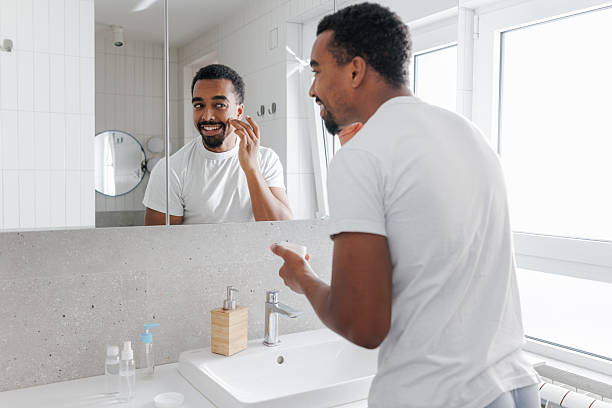 Young man applying a face cream in the bathroom