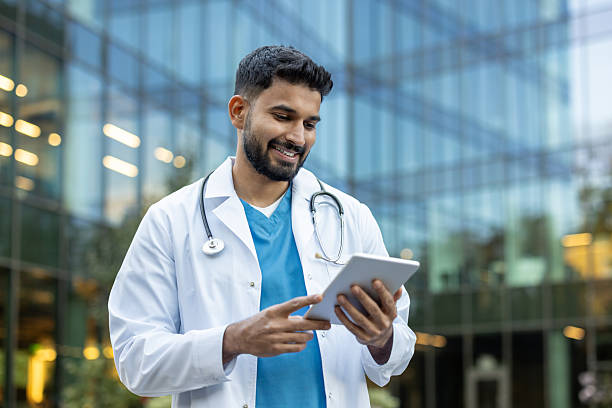 istock Smiling doctor using a tablet in front of the hospital 2245502319