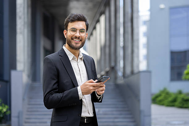 istock A smiling businessman in a suit is using his smartphone outside a modern building. 2245503153