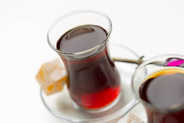 Two glasses of Turkish tea are displayed with sugar cubes on a small plate, creating a cozy setting.