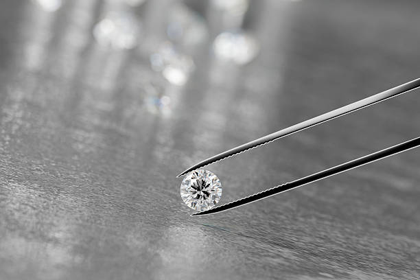 istock Brilliant crystal diamond and tweezers on a black background with objects soft focusing 3d rendering 2245510374