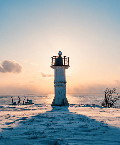 istock A white lighthouse stands tall on a snowy shore, casting a long shadow as the sun sets over the frozen sea 2245510538