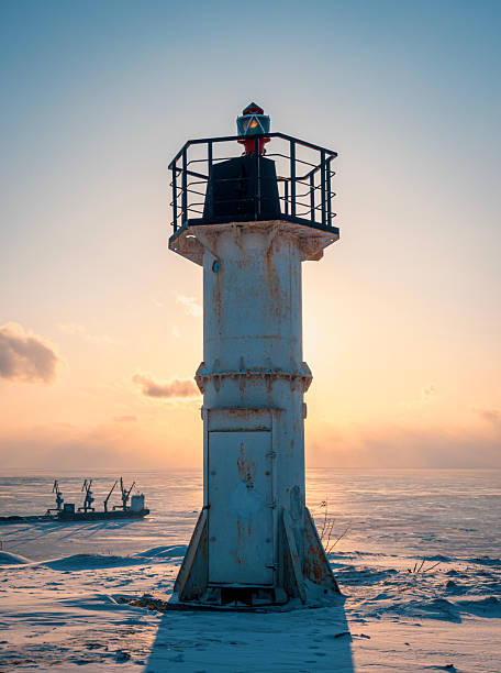 istock A white lighthouse stands tall on a snowy shore, casting a long shadow as the sun sets over the frozen sea 2245510573