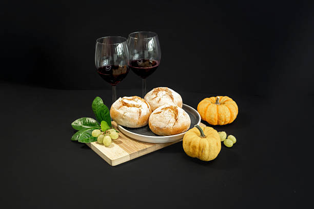 Autumn still life with pumpkins and homemade freshly baked buns arranged on a black background. Warm rustic mood, seasonal harvest, cozy food concept.