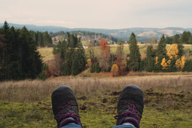 Hikers sit on a wooden flooring above the carpathian mountain valley and enjoy colorful clouds in a light of sunset. Instagram stylisation.