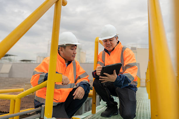 istock Maintenance engineers on a refinery rooftop discuss machinery upgrades. Industrial background with crude oil storage tanks, pipelines, and steel structures highlights safety, innovation, and sustainable energy in fuel and power generation industry. 2245515899