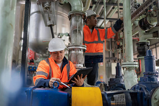 istock Two engineers in safety gear inspect pumps and valve systems inside a lubricant manufacturing plant. They analyze real-time data on a digital tablet to ensure efficient, safe, and sustainable oil production with modern technology and precision. 2245515909
