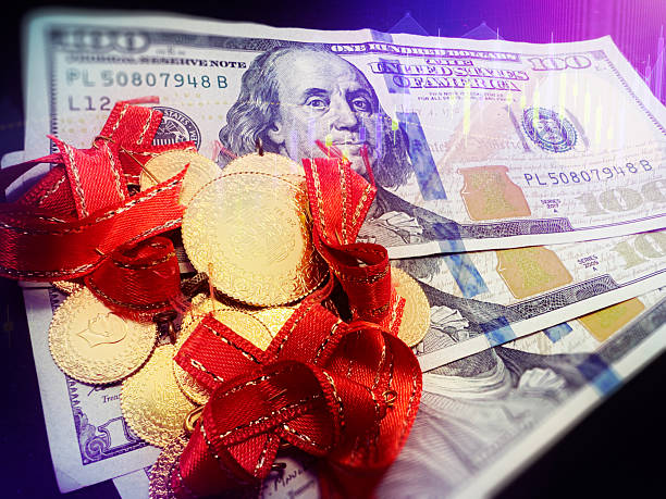 Close-up view of traditional Turkish gold coins decorated with red ribbons placed on US 100 dollar bills, symbolizing wealth, investment, and currency exchange between Turkey and the United States.
