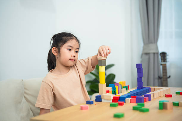 istock Young girl engaging in creative play with colorful building blocks, developing fine motor skills, and enhancing cognitive abilities in a bright room 2245519054