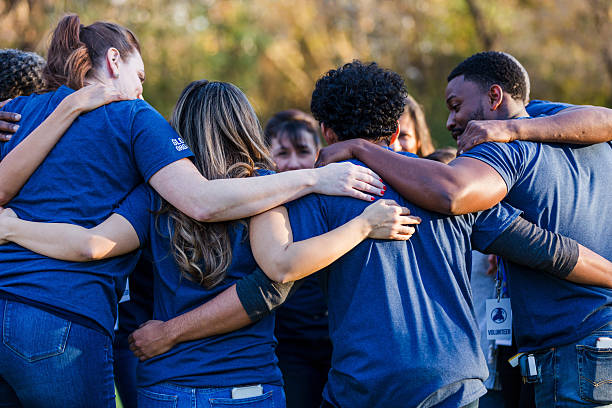 istock Diverse group of volunteers in a circle, embracing each other outdoors for unity and support. 2245519782