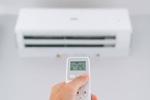 istock Close up of female hand using remote control to set air conditioner temperature at 25 degrees 2245520608