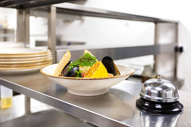 Chef prepares a seafood dish with mussels and vegetables in a lively kitchen setting.