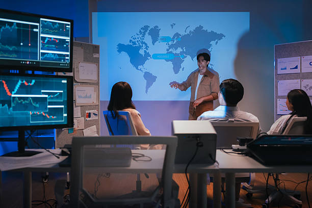 istock young Asian software development manager leads a late-night office discussion with his executive team, mentoring developers and analyzing source code to guide programming and project development 2245524657