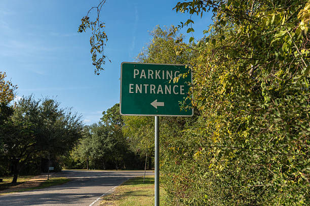 Green Parking Entrance Sign with Directional Arrow at Tree-Lined State Park Road in Texas