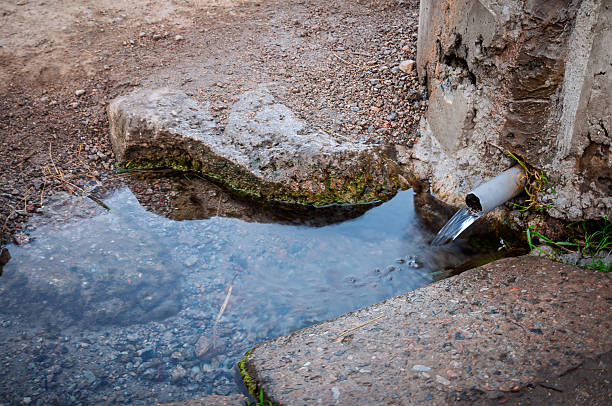 istock Fresh water flowing from a pipe into a small pool of water 2245527423