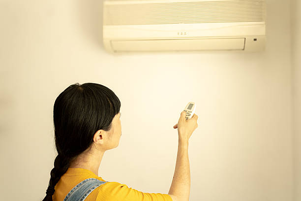 istock Woman adjusting air conditioner with remote control at home 2245529964