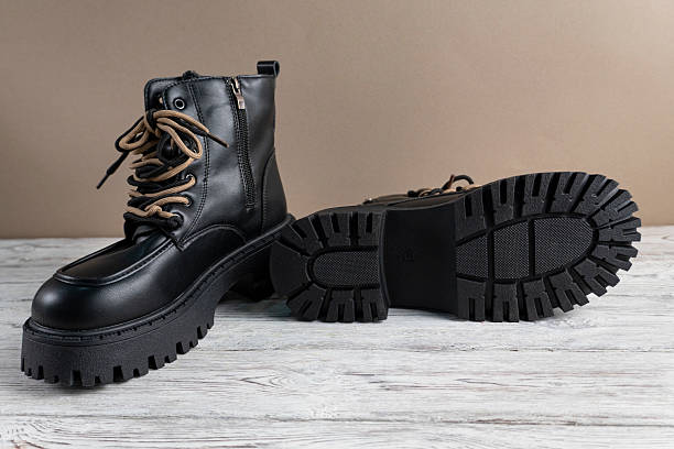 istock Black leather boots with beige laces on light background 2245530612