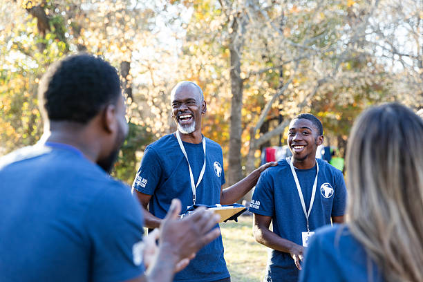 istock Smiling multiracial people collaborate outdoors wearing matching shirts and lanyards, enjoying teamwork. 2245532731