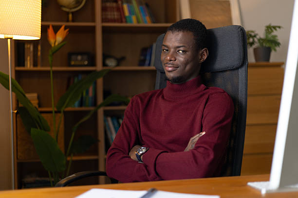 istock Confident young black man smiling, sitting at desk in home office workstation 2245533045
