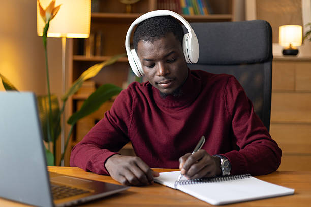 istock Young man focused on e-learning, taking an online course at his desk 2245533136
