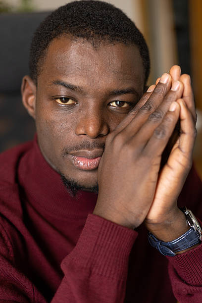 istock Young african man thinking or praying with hands together looking at camera 2245533294