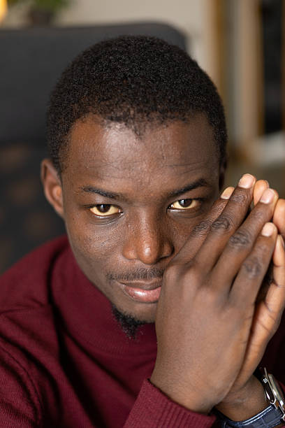 istock Young adult man looking with serious expression while clasping hands 2245533296