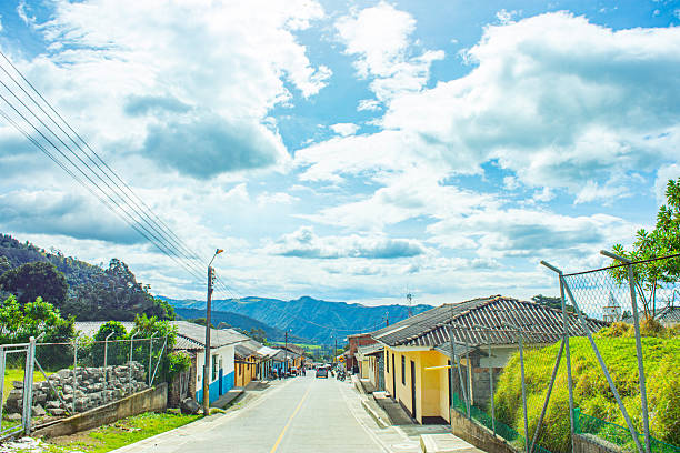 A beautiful landscape of a road in Purace, Cauca, with colorful houses and rolling hills under a clear blue sky.