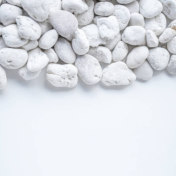White pebble stones on white background with copy space.