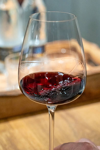 istock Hand swirling red beverage in wine glass for tasting 2245542255