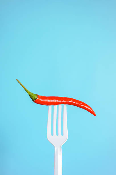 istock Fresh red chilli on white plastic fork with blue background. Hot and Spicy concept. 2245543288