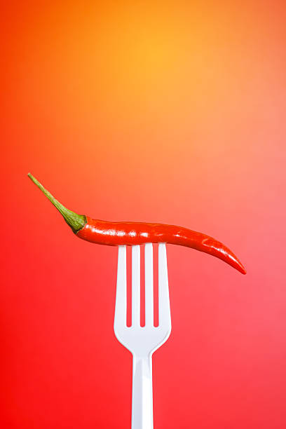 istock Fresh red chilli on white plastic fork with red background. Hot and Spicy concept. 2245543295