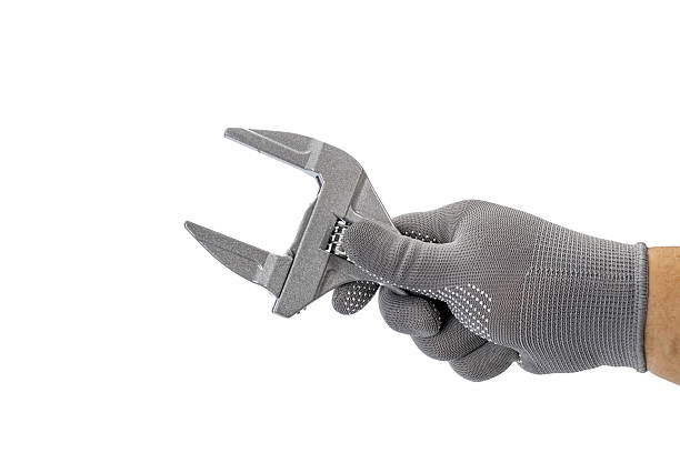 istock A gloved hand holds medium width wrench against white background, showcasing tool used for tightening or loosening nuts and bolts 2245544123