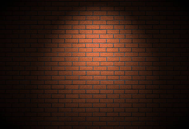 Night time street light brick wall background alley texture. Intense vibe with no people and spotlight on empty building real backdrop. Bricks constructed in running bond pattern.