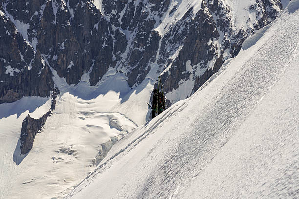 A skier is skiing down a snow covered mountain. The skier is wearing a black jacket and is surrounded by snow