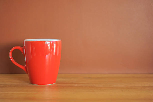 istock Red ceramic coffee cup on wood table and brown background with copy space 2245548142