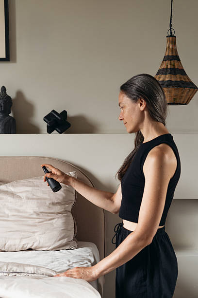Woman refreshing bedding in a cozy, modern bedroom space