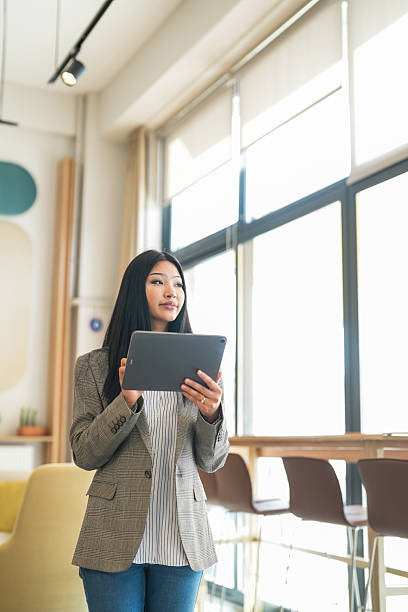 istock Confident businesswoman standing with tablet in bright modern office 2245551059