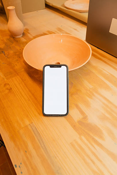 istock Smartphone with blank screen on wooden table in pottery studio 2245551380