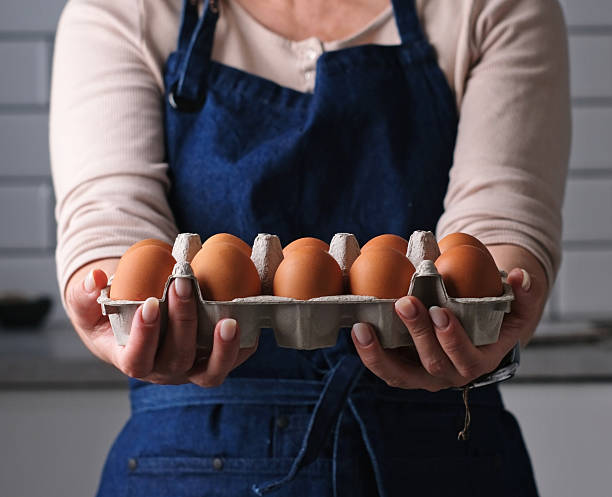 istock Woman In Apron Showing Egg Tray In Kitchen 2245552108