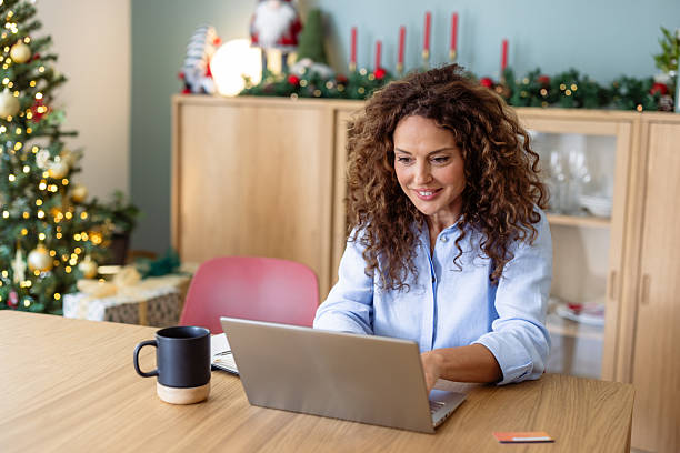 istock Woman using a laptop at a dining table at home during Christmas 2245552949