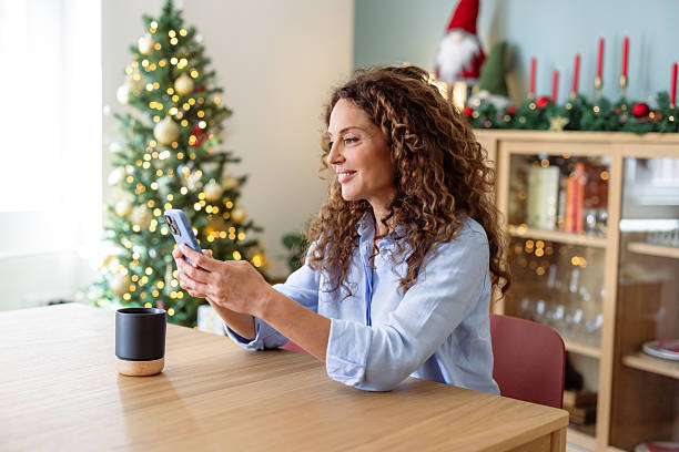 istock Woman at home using smartphone by a Christmas tree 2245553137