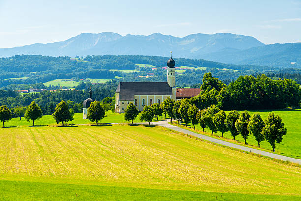 Wallfahrtskirche Wilparting Saint Marinus Church on Sunny Summer Day. Green Meadow and Mountains. Bavaria, Germany