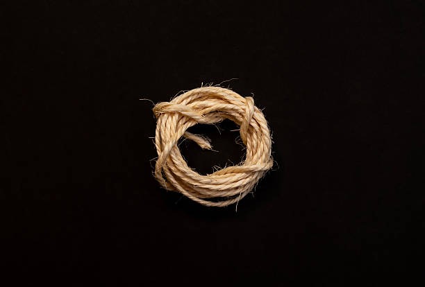 istock Coiled hemp rope tied in a knot on black background symbolizing strength 2245553806