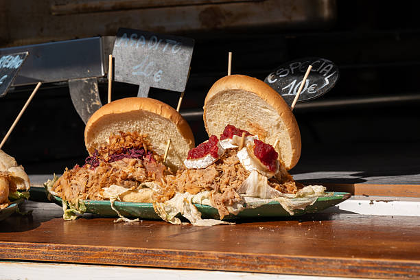 Delicious pulled pork sandwiches with cabbage and brie in sunlit market.