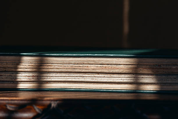 Vintage book with sunlight and shadows on rustic wooden table.