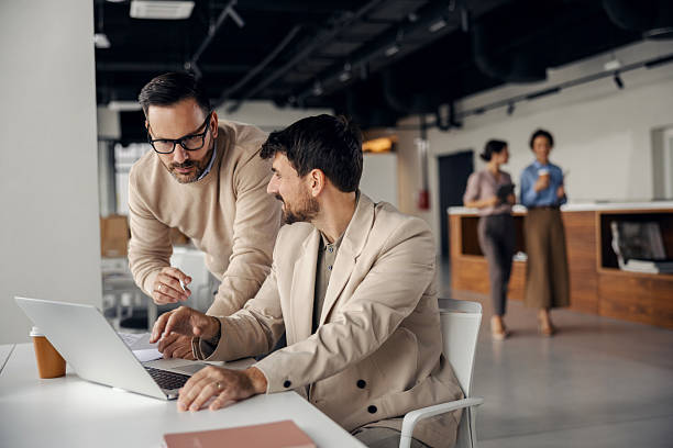 istock Businessmen collaborating on laptop in modern office 2245556516